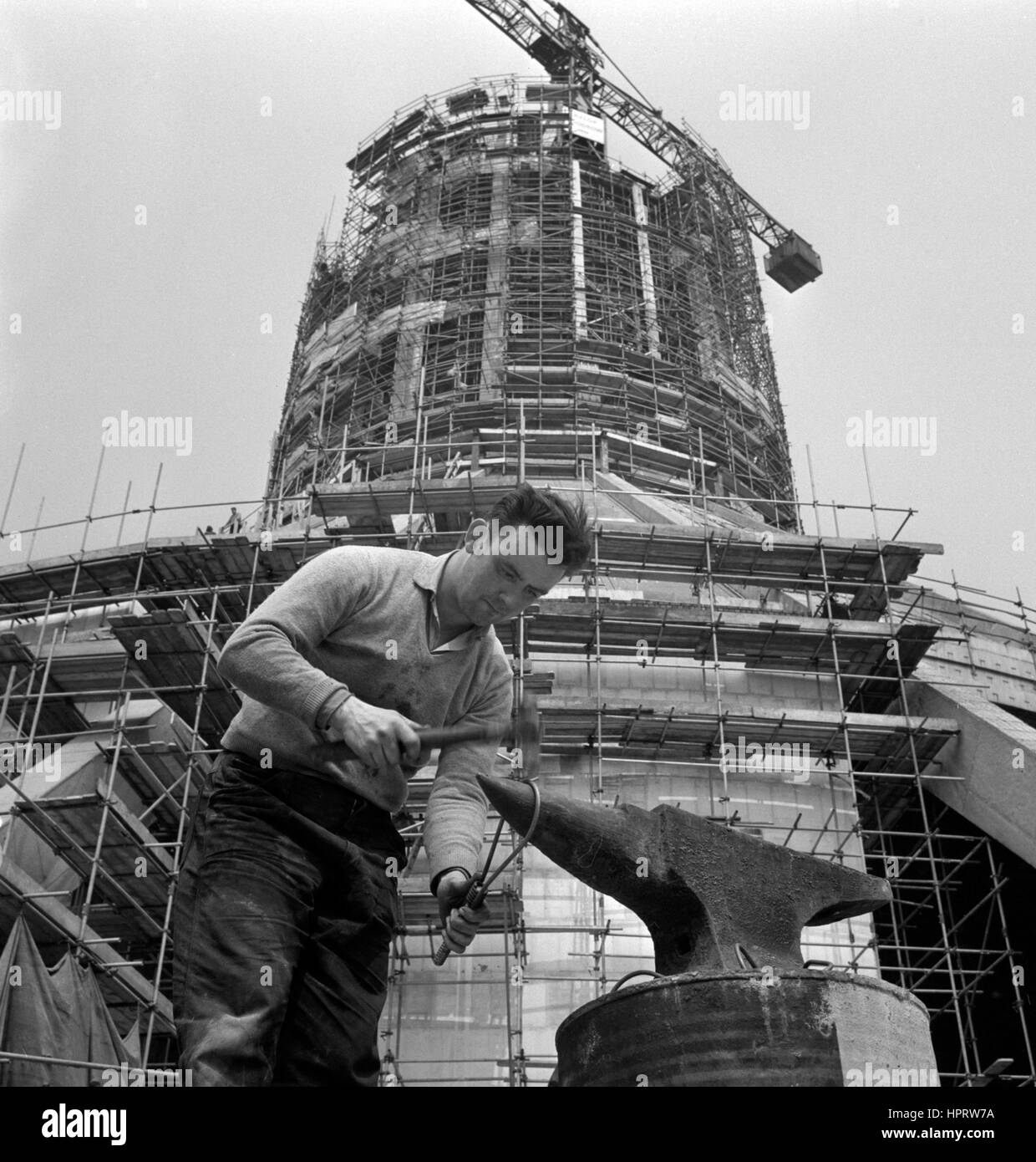 Eddie Holmes, un installatore-saldatore, fa uso di un antico strumento - un'incudine - come egli svolge la sua parte nella costruzione di un nuovo edificio moderno, la Cattedrale Metropolitana di Cristo Re a Liverpool. Foto Stock