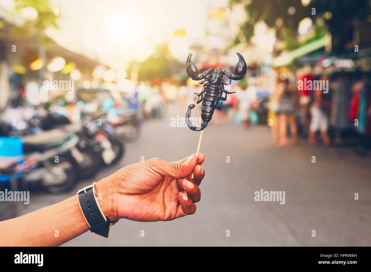 La mano del produttore thailandese che mostra arrosto di scorpione. Strada del mercato nel centro di Bangkok, Tailandia. Foto Stock