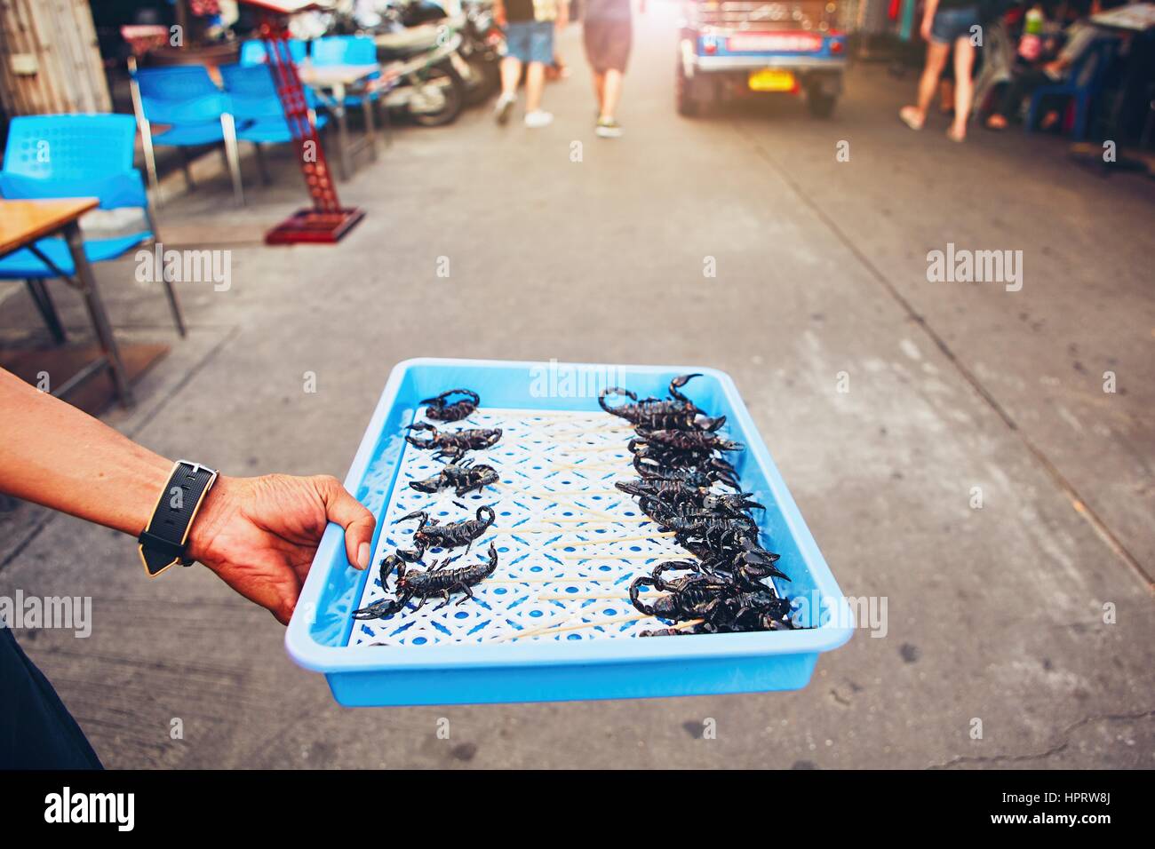 La mano del produttore thailandese che mostra arrosto di scorpione. Strada del mercato nel centro di Bangkok, Tailandia. Foto Stock