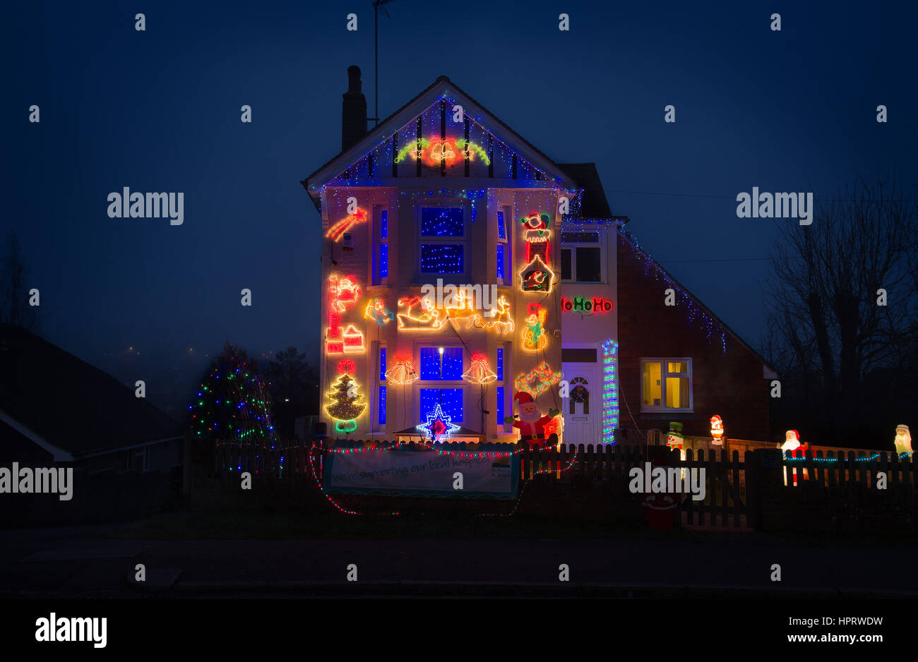 Casa suburbana a Natale. Blu scuro cielo nebbioso dietro una luminosa casa. Foto Stock