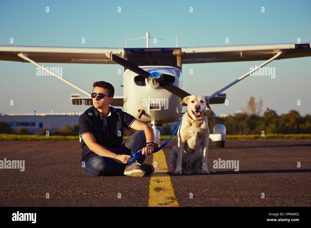 Giovane pilota con il cane sono seduti nella parte anteriore del velivolo Foto Stock
