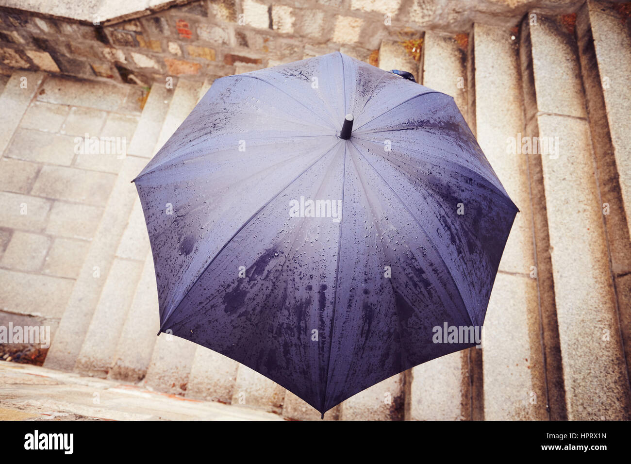 Pioggia in città - Uomo con ombrello blu Foto Stock
