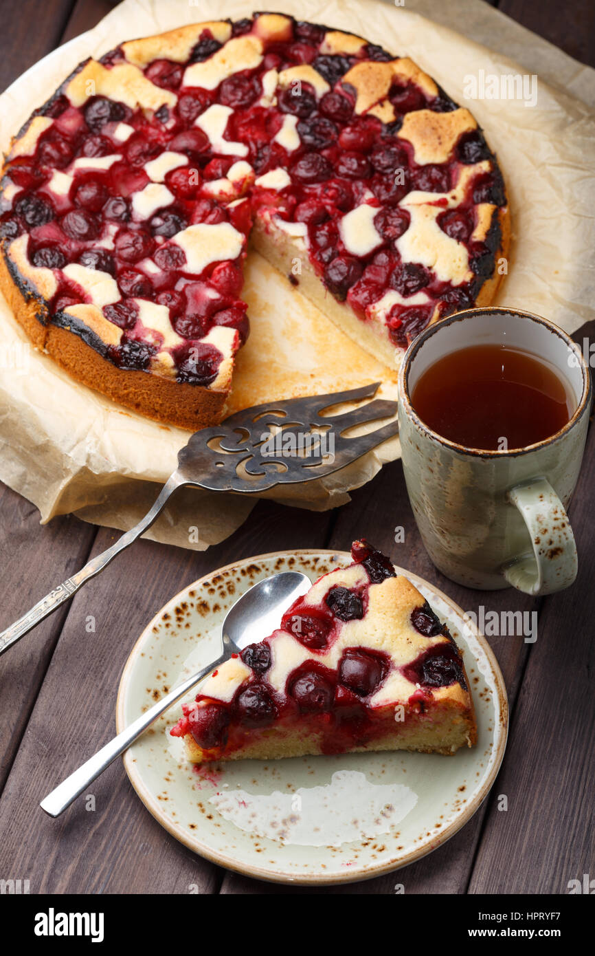 In casa torta di ciliegie con tazza da tè sul tavolo di legno. Foto Stock