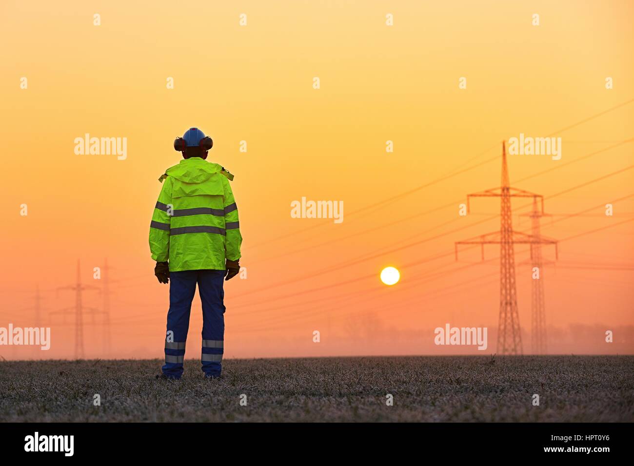 Lavoratore è la visione di piloni di elettricità e sottostazione al sunrise Foto Stock