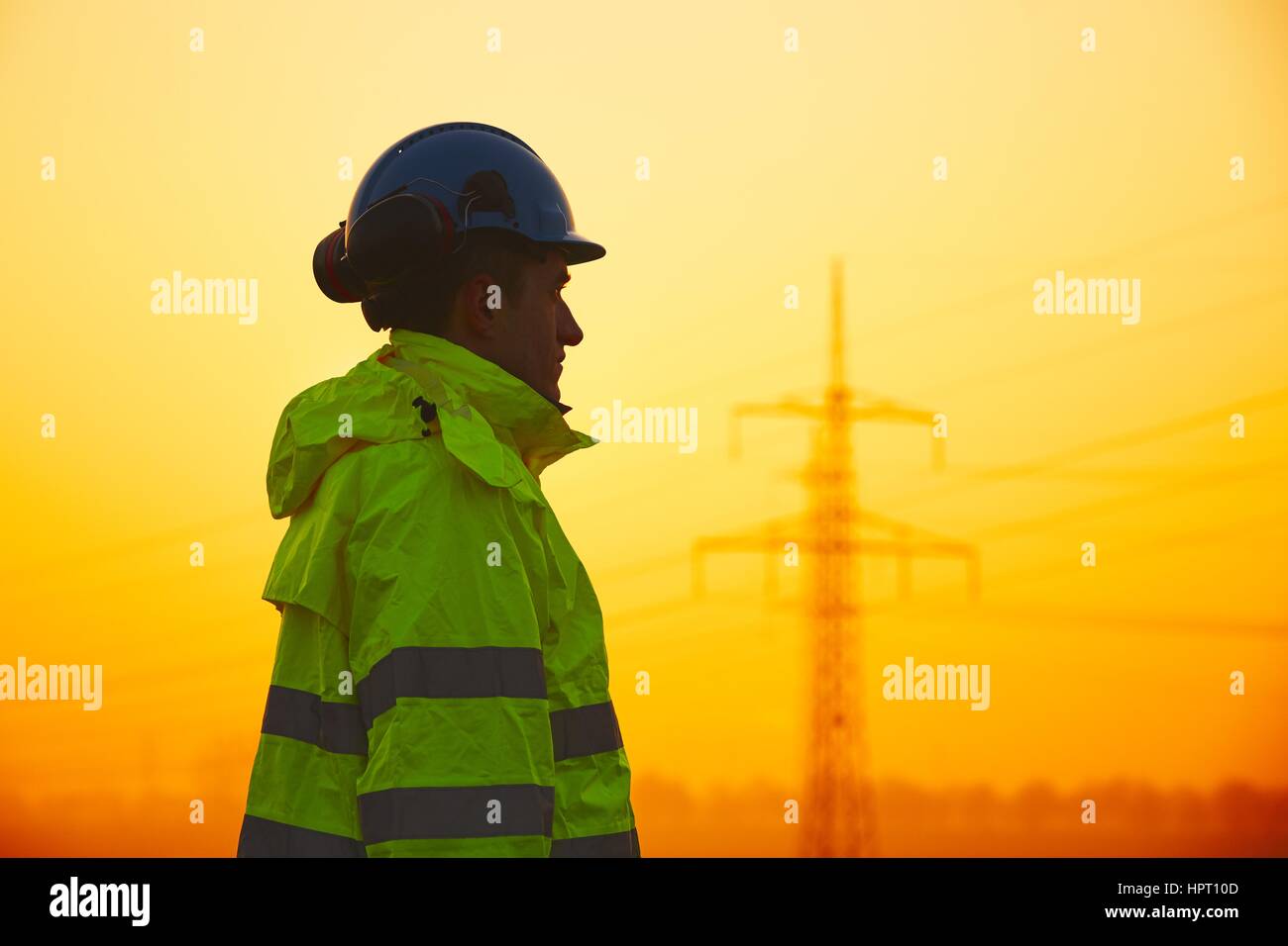 Lavoratore è la visione di piloni di elettricità e sottostazione al tramonto Foto Stock
