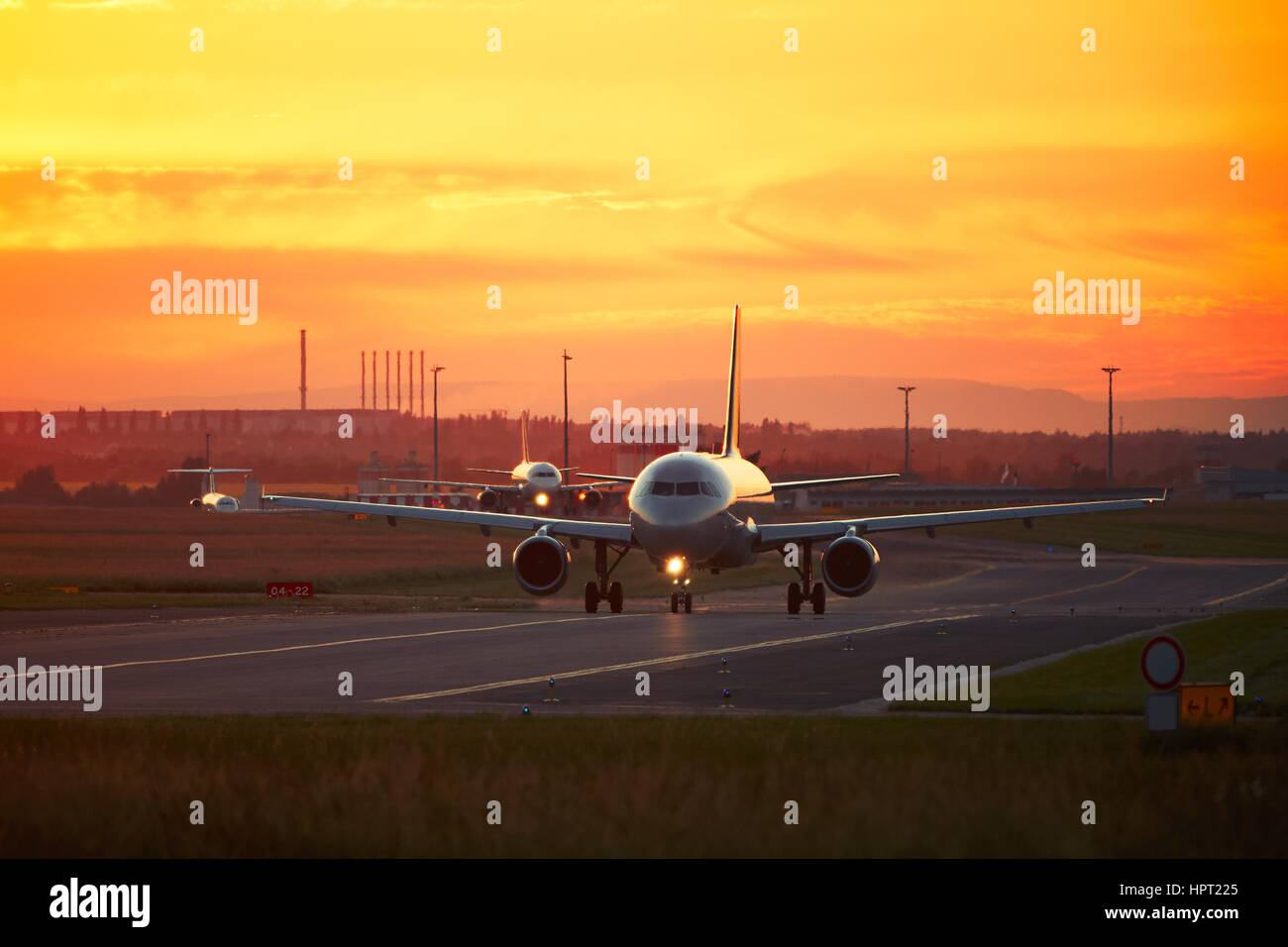 Traffico aeroportuale al tramonto dorato. Gli aerei sono in rullaggio per la pista di decollo. Foto Stock