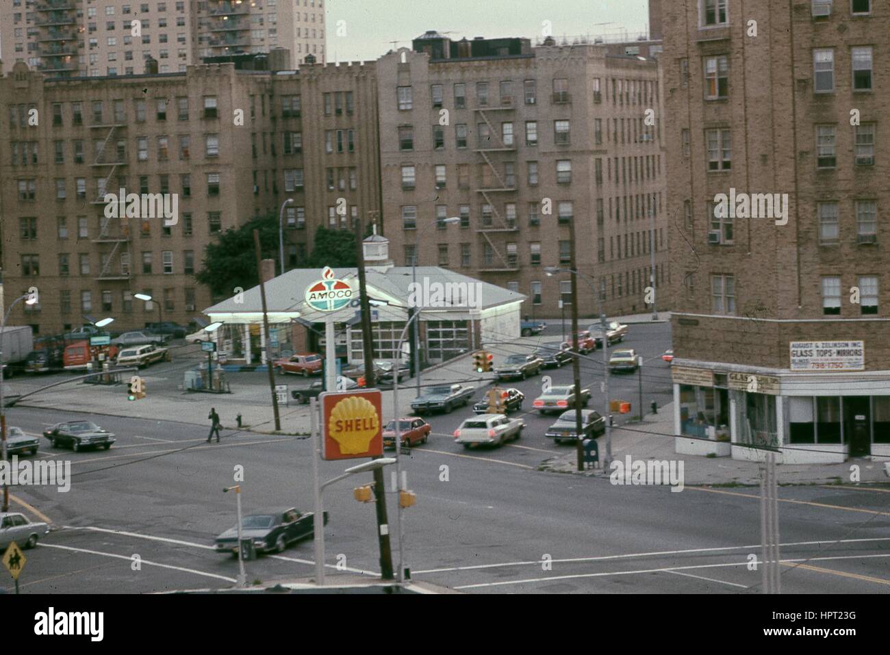 Macchine passano attraverso un incrocio vicino Amoco e Shell gas stazioni, con la vetrina di agosto e Zelkinson glass company visibile, nel Bronx, New York, New York, 1976. Foto Stock