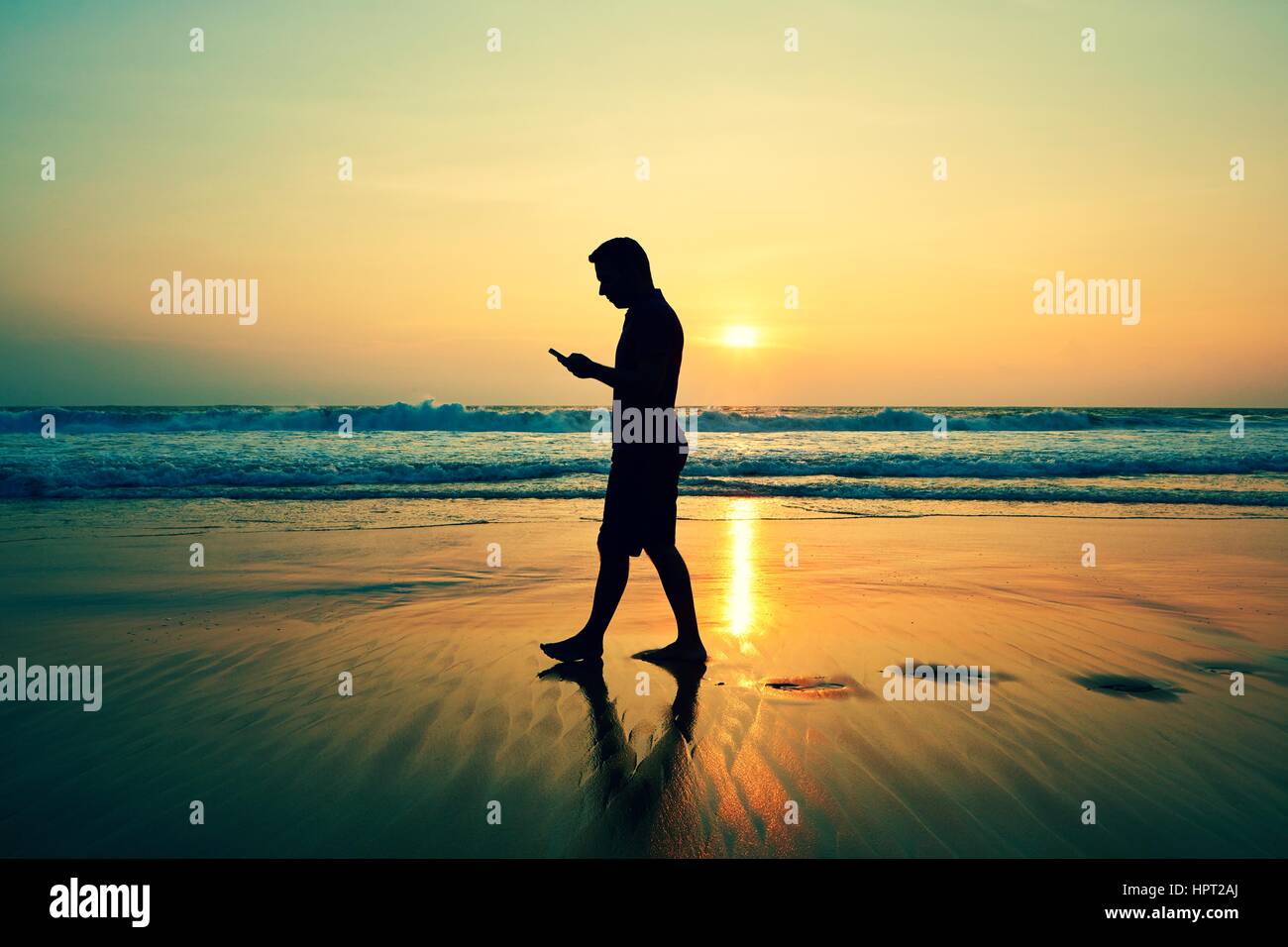 Silhouette di un giovane uomo sulla spiaggia al tramonto Foto Stock