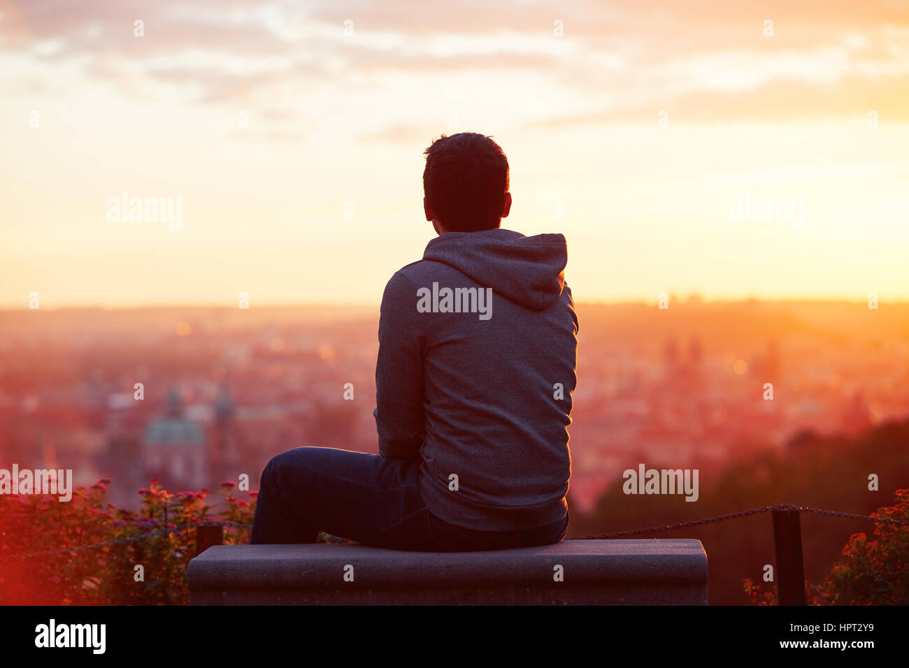 Giovane uomo è guardando il sorgere del sole. Foto Stock