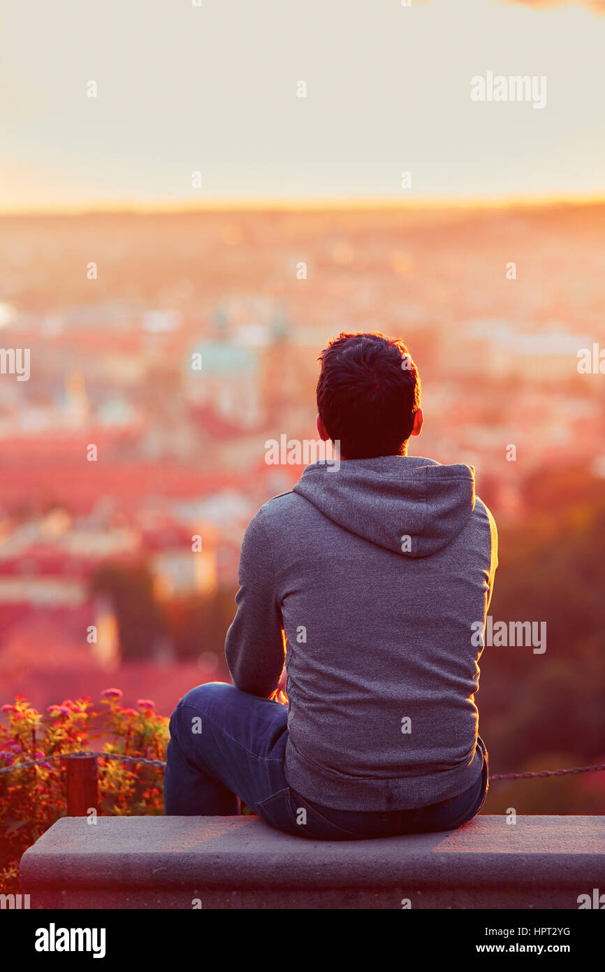 Giovane uomo è guardando il sorgere del sole. Foto Stock