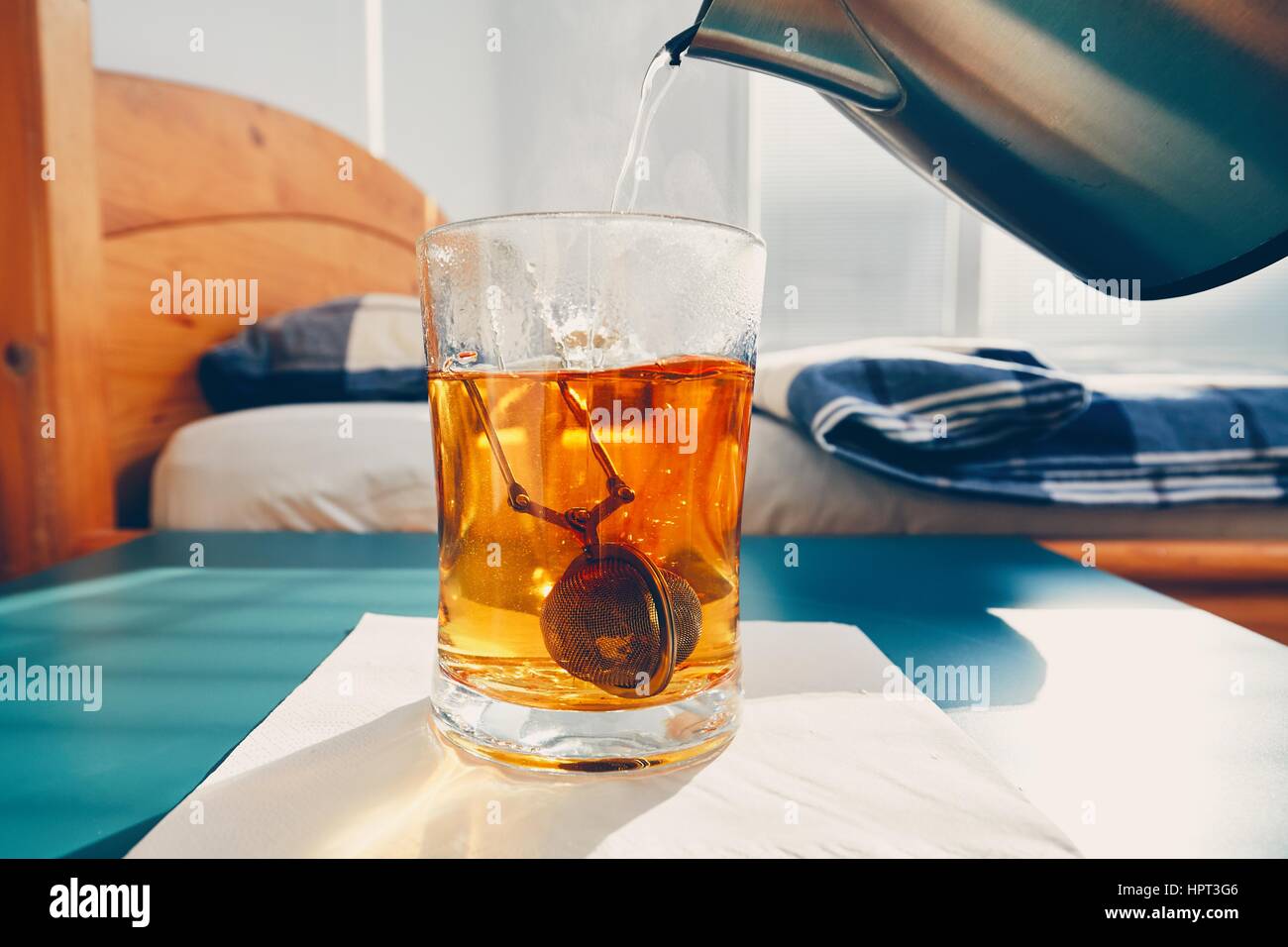 Il tè caldo in tazza di vetro sul comodino in camera da letto. Foto Stock