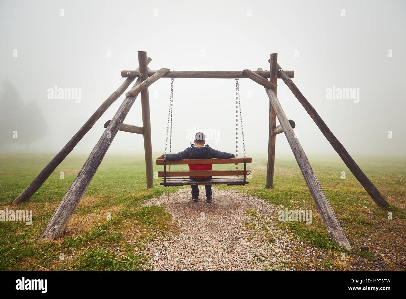 Triste uomo sull'altalena nella nebbia misteriosa Foto Stock