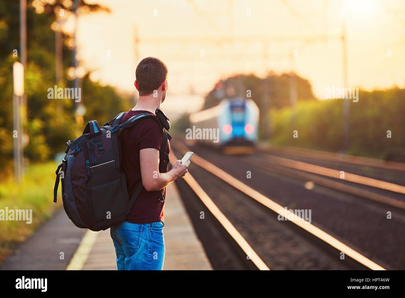 Traveler è tardi alla stazione ferroviaria. Giovane uomo con zaino perso il treno e in attesa per il prossimo. Foto Stock