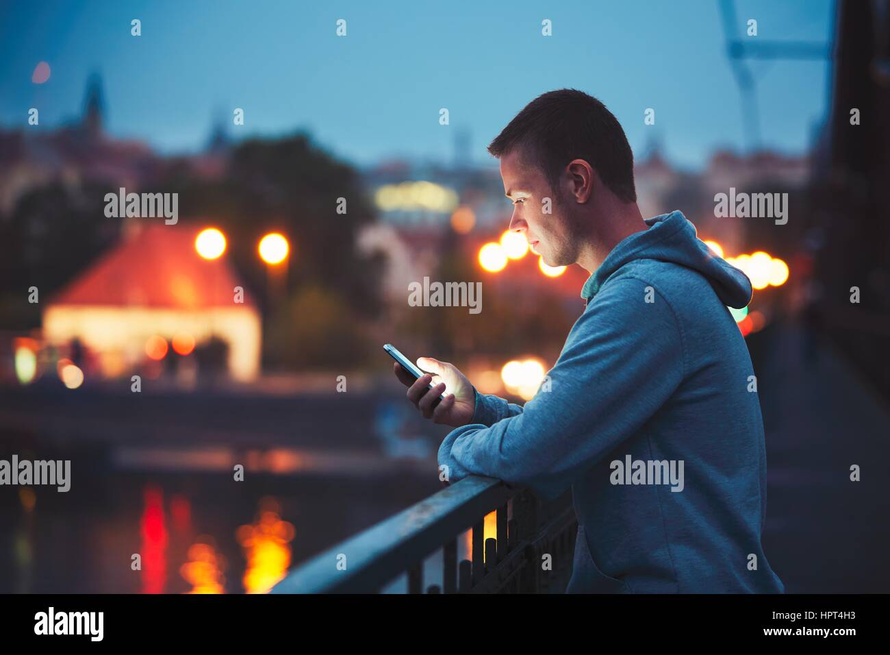 Solo nella notte in città con il telefono cellulare. Bello dreamy uomo messaggio di lettura (o cercando sul video) sul suo smartphone. Foto Stock