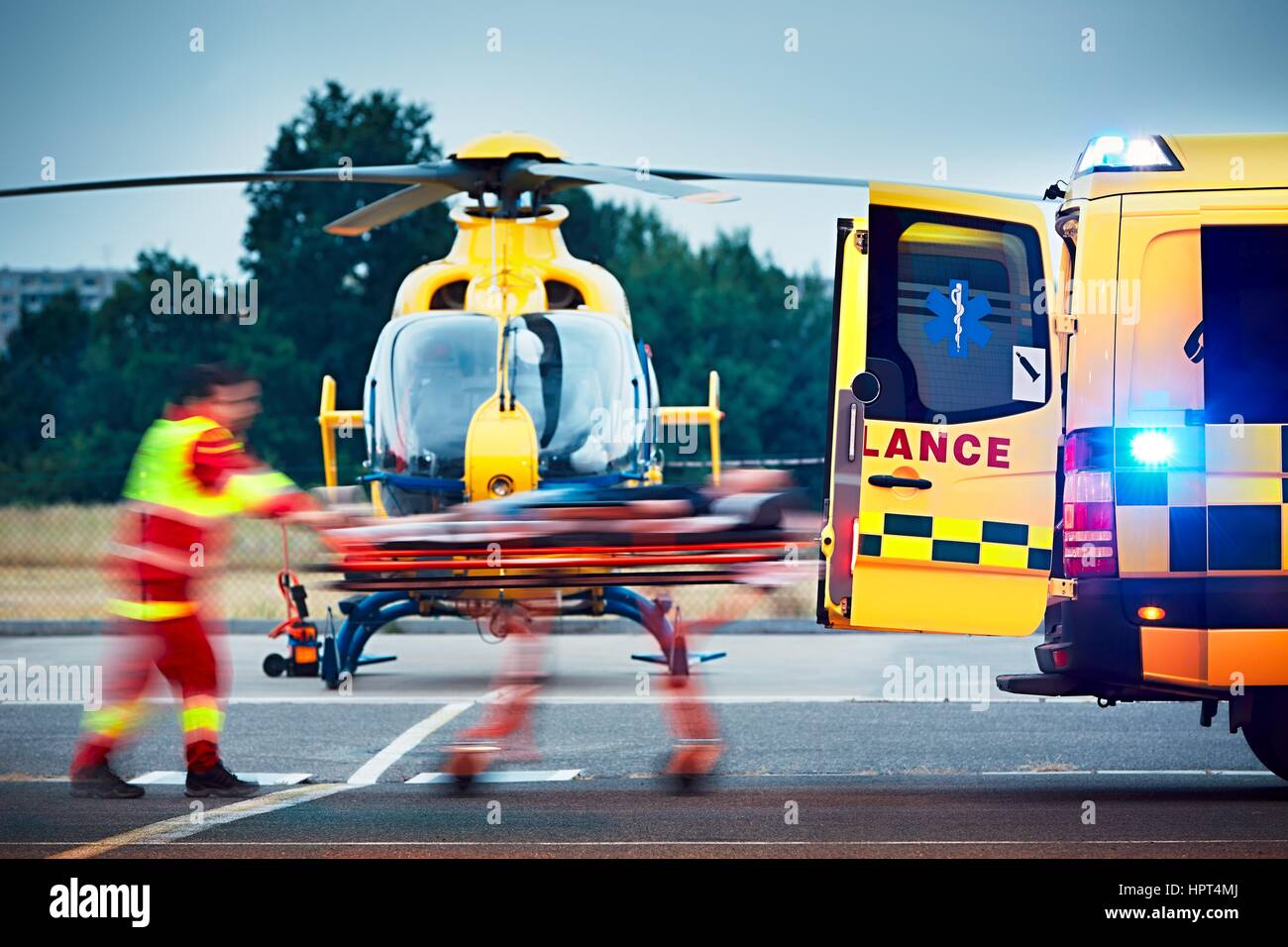 La cooperazione tra Air rescue service e il servizio di emergenza medica sul terreno. Paramedico è tirando barella con il Paziente in ambulanza. Foto Stock