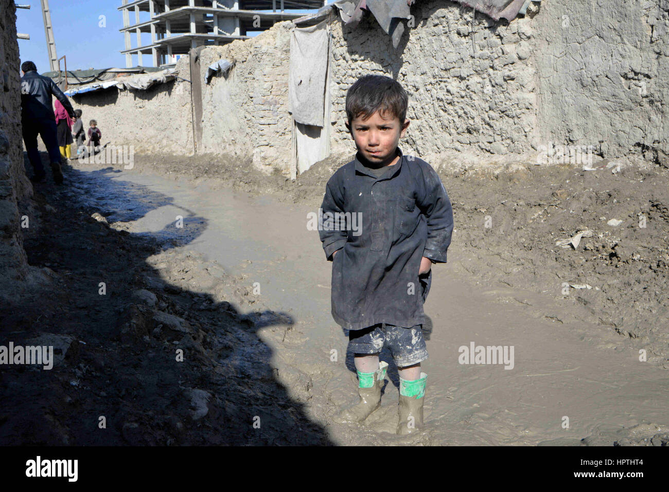 A Kabul, Afghanistan. Il 23 febbraio, 2017. Un ragazzo sta alla strada fangosa tra gli edifici di fango nel nord del distretto urbano di Kabul, Afghanistan, nel febbraio 23, 2017. L'inverno è quasi tappezzate in Afghanistan, che toccano la vita delle famiglie povere, particolarmente per coloro che non dispongono di apparecchiature di riscaldamento, acqua pulita o cibo sufficiente per far fronte alle basse temperature. Nella parte settentrionale del distretto urbano di Kabul, molti sono ancora vive in edifici di fango e non hanno i soldi per acquistare qualsiasi legna per il fuoco. Credit: Iam egli/Xinhua/Alamy Live News Foto Stock