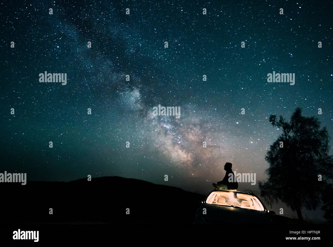 Austria, Mondsee, silhouette di un uomo seduto sul tetto del veicolo sotto il cielo stellato Foto Stock