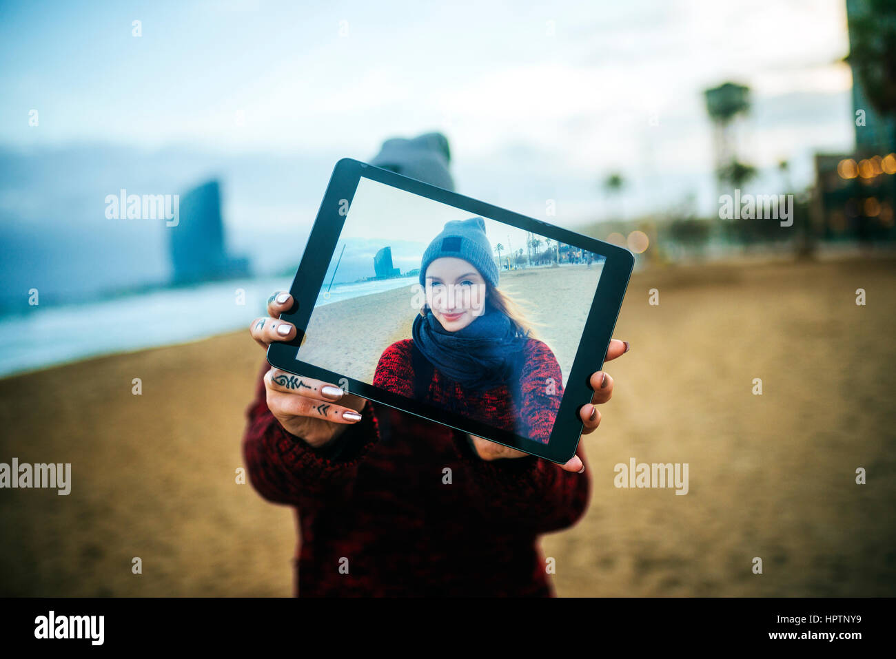 Giovane donna sulla spiaggia in inverno prendendo un selfie con una compressa Foto Stock
