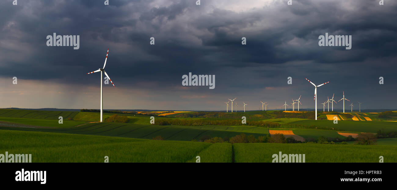 I campi contrassegnati con l'energia eolica turbine in pioggia blu scuro nuvole Foto Stock