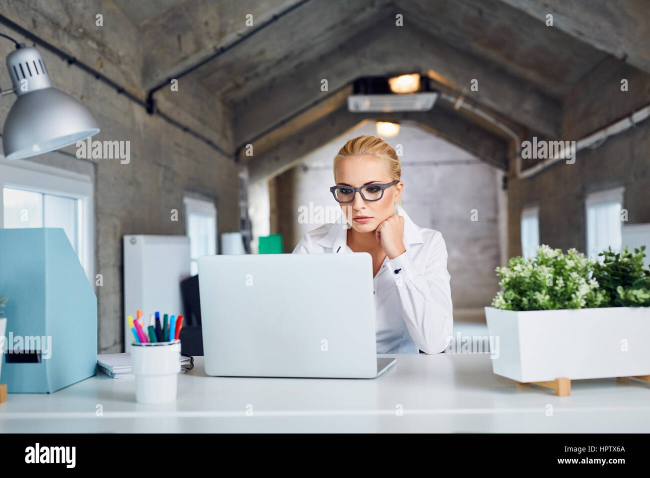 Considerato occupato business donna lavora su computer portatile presso un ufficio moderno Foto Stock