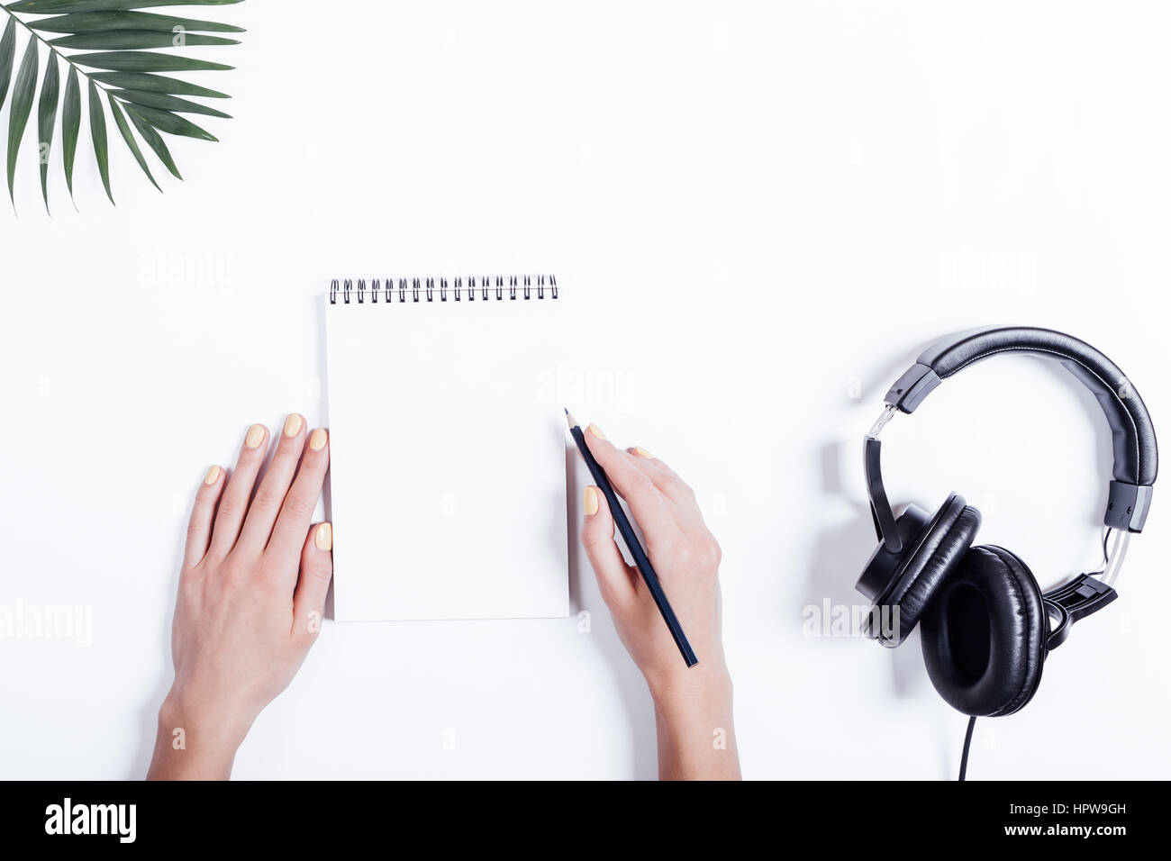 Mani femminili, notebook e cuffie su un tavolo bianco vista superiore Foto Stock