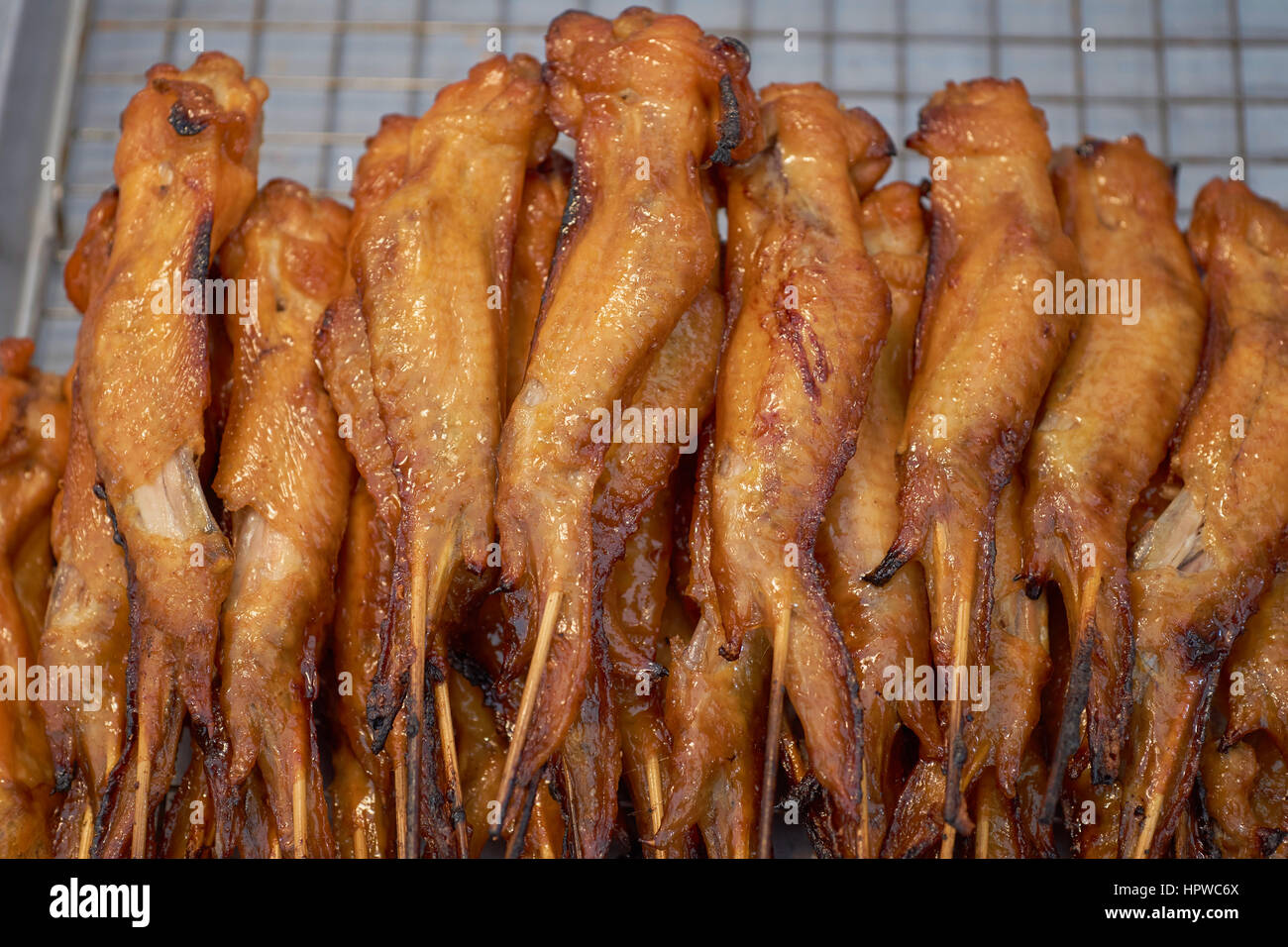Alette di pollo fritte su bastoni di kebab - grigliato in un mercato della Thailandia Foto Stock