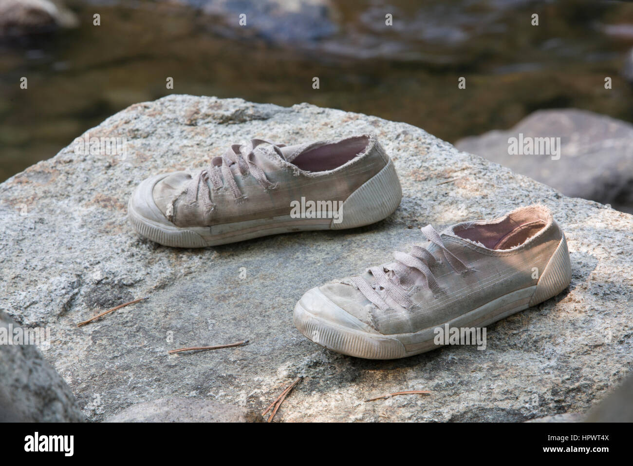 Misura di bambino scarpe da tennis a sinistra su una roccia accanto a Donner Creek, Donner Memorial State Park, Truckee, CA. Foto Stock