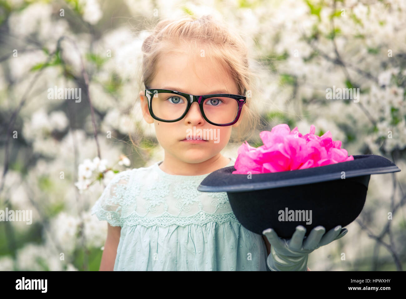 Funny Girl in occhiali e guanti e con hat giocare in giardino di primavera. Foto Stock