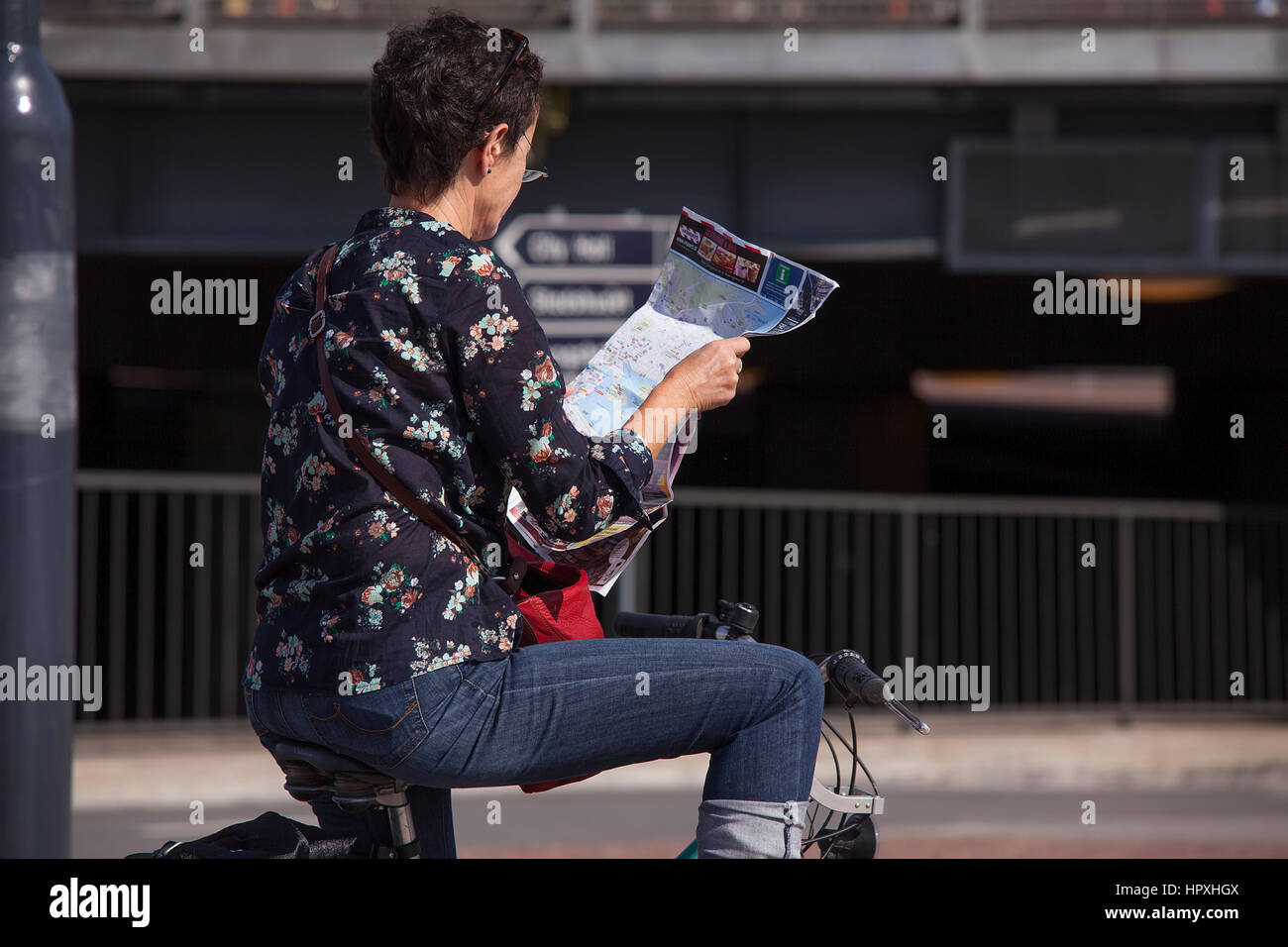 Donna su una bicicletta la lettura di una mappa. Foto Stock