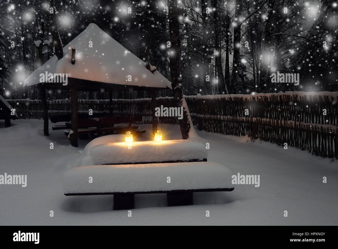 Le luci di natale nella foresta a notte di Natale. Di notte sullo sfondo di Natale con le candele. Nevicate in inverno in giardino. Foto Stock