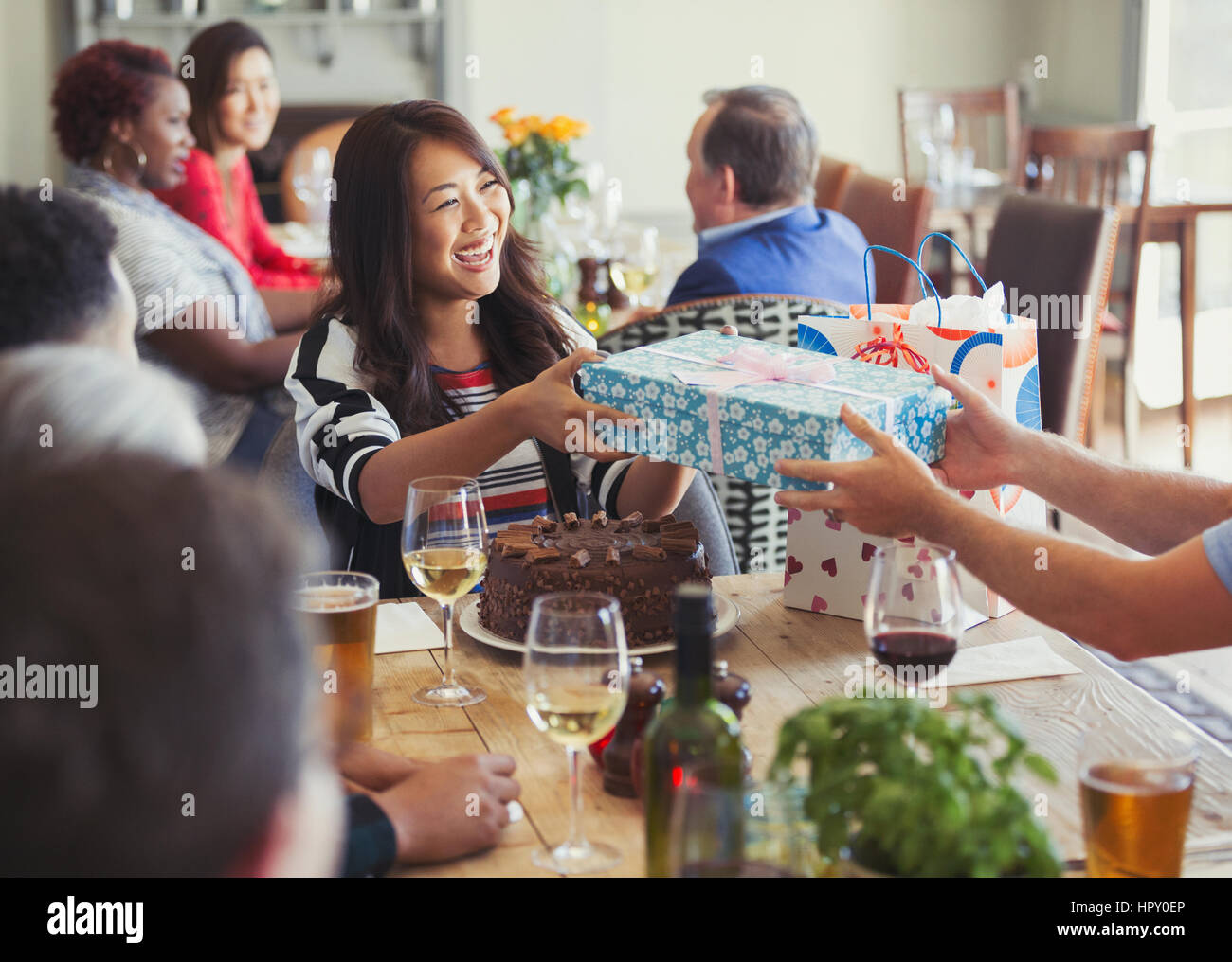 Donna sorridente ricevere regalo di compleanno da amico al ristorante tabella Foto Stock