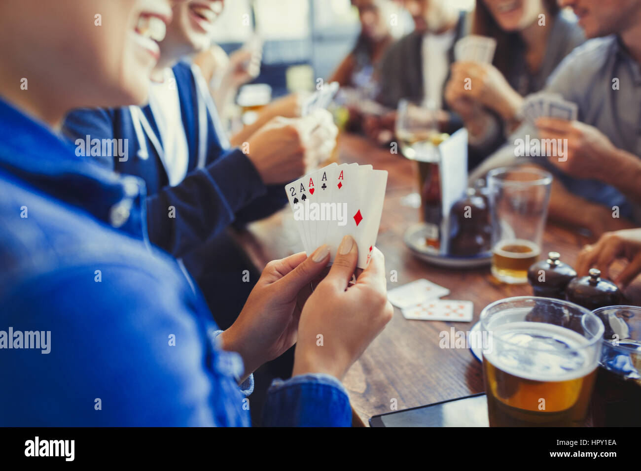 Donna che mantiene aces quattro di un tipo, giocando a poker e bere birra con gli amici a tavola in bar Foto Stock