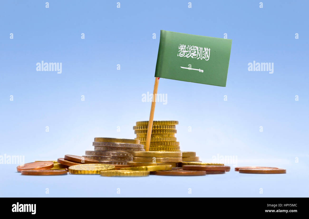 Bandiera della Arabia Saudita in una pila mista di monete europee e uno sfondo blu.(serie) Foto Stock