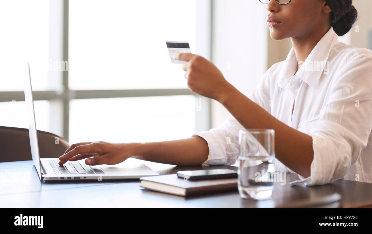 Volto americano africano donna fare il bonifico online utilizzando la sua carta di credito per verificare la transazione, per assicurare i suoi rapporti di affari Foto Stock