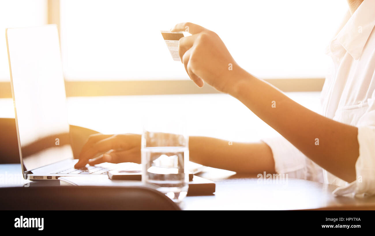 Decapitati raccolto di una femmina nero occupato con un computer portatile per effettuare pagamenti online utilizzando la sua carta di credito. Foto Stock