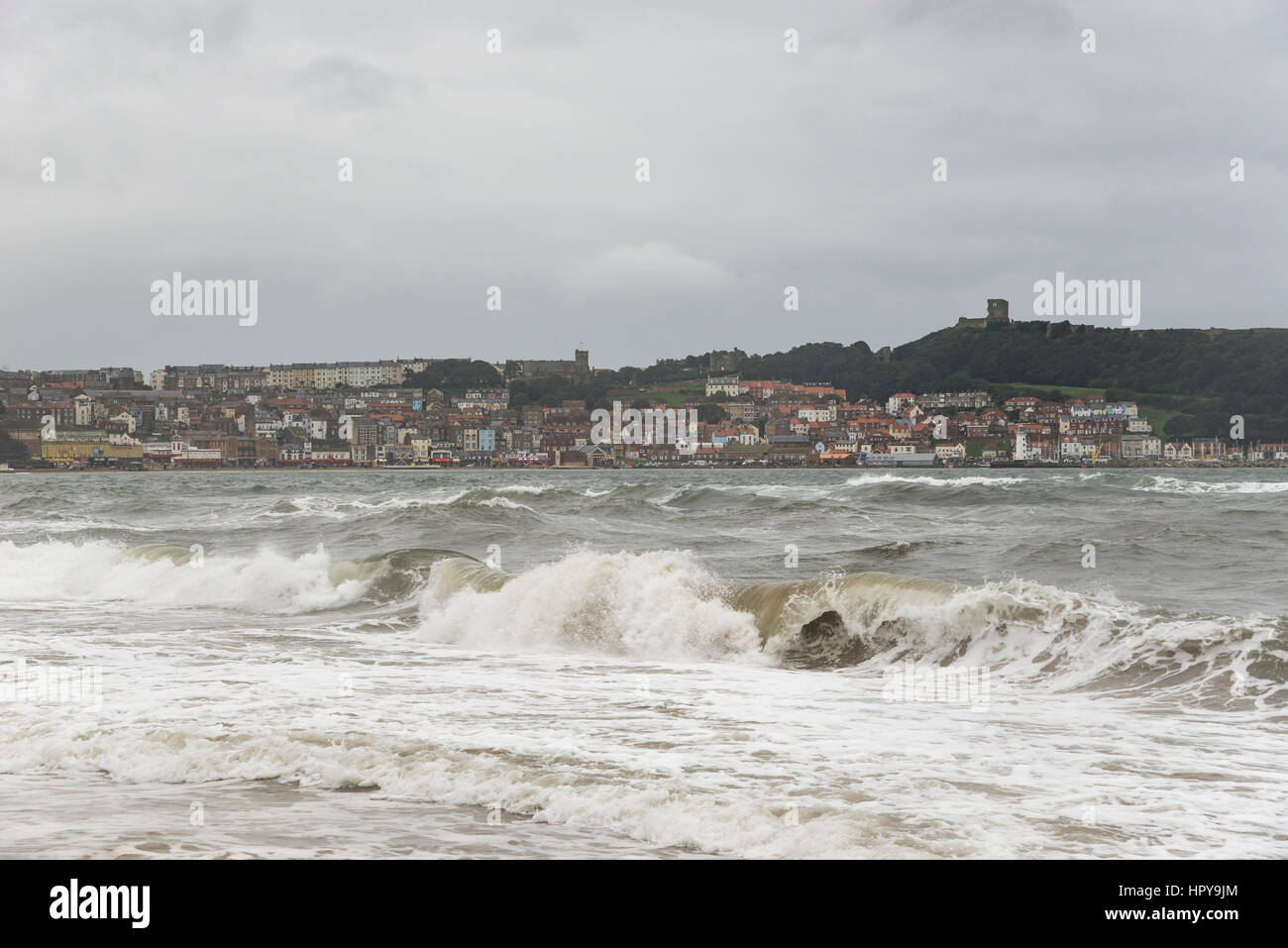 Mare mosso a Scarborough, North Yorkshire sulla costa orientale dell'Inghilterra. Vista del porto e del castello di distanza. Foto Stock