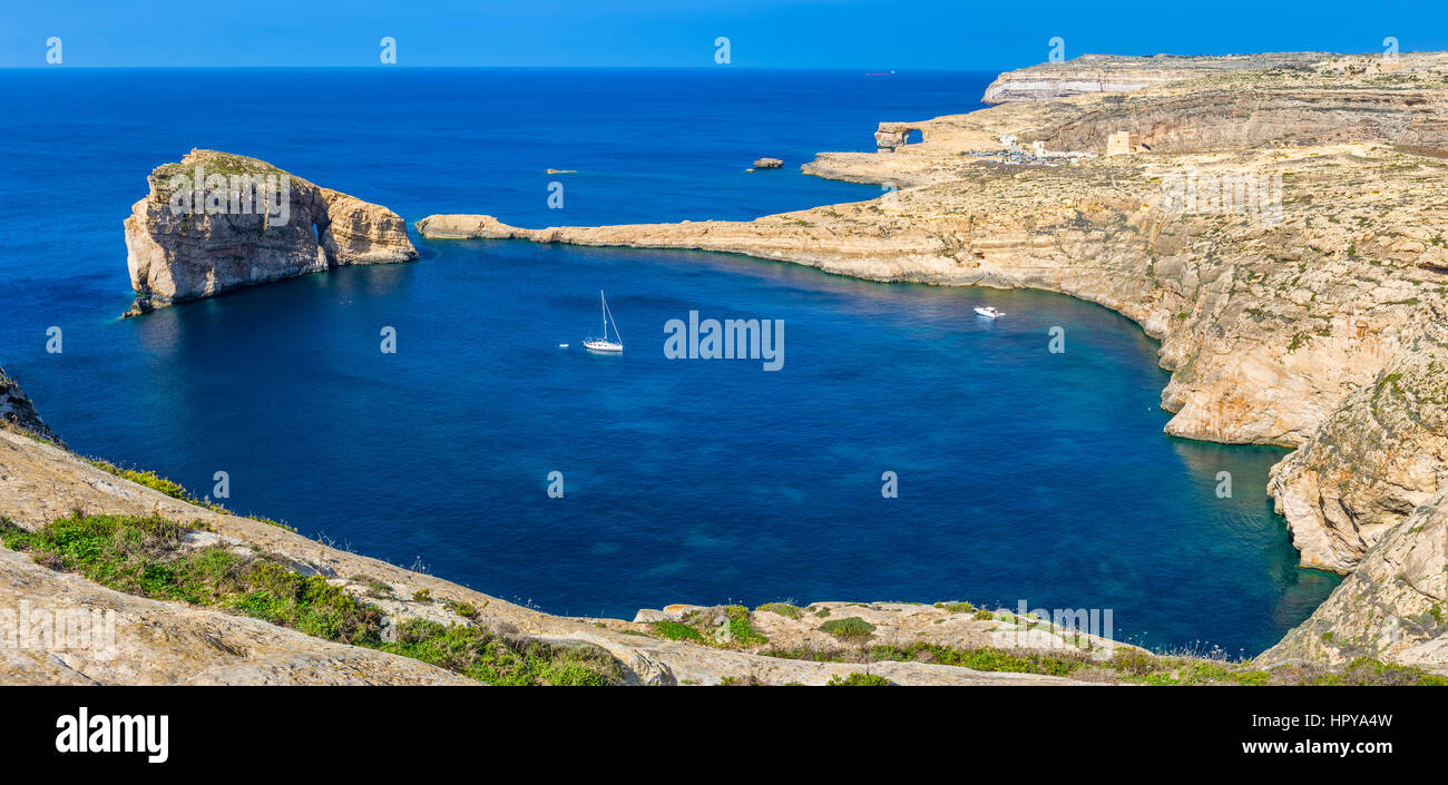A Gozo, Malta - panoramica vista sullo skyline di Dwejra Bay con la roccia del fungo, Azure Window e la barca a vela su una bella e calda giornata d'estate Foto Stock