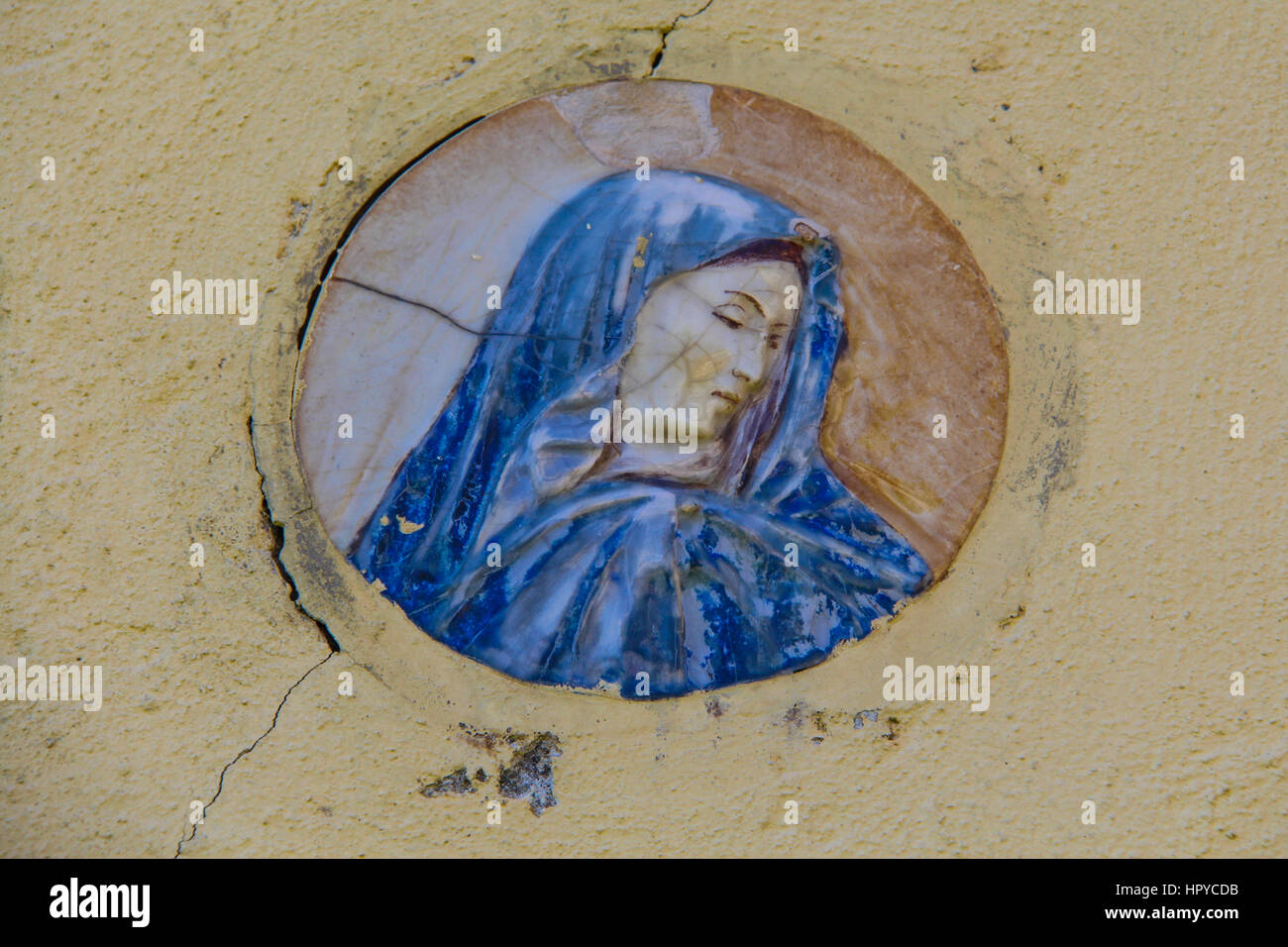 Close-up di un piccolo murale della Vergine Maria su di un intonaco giallo parete Foto Stock