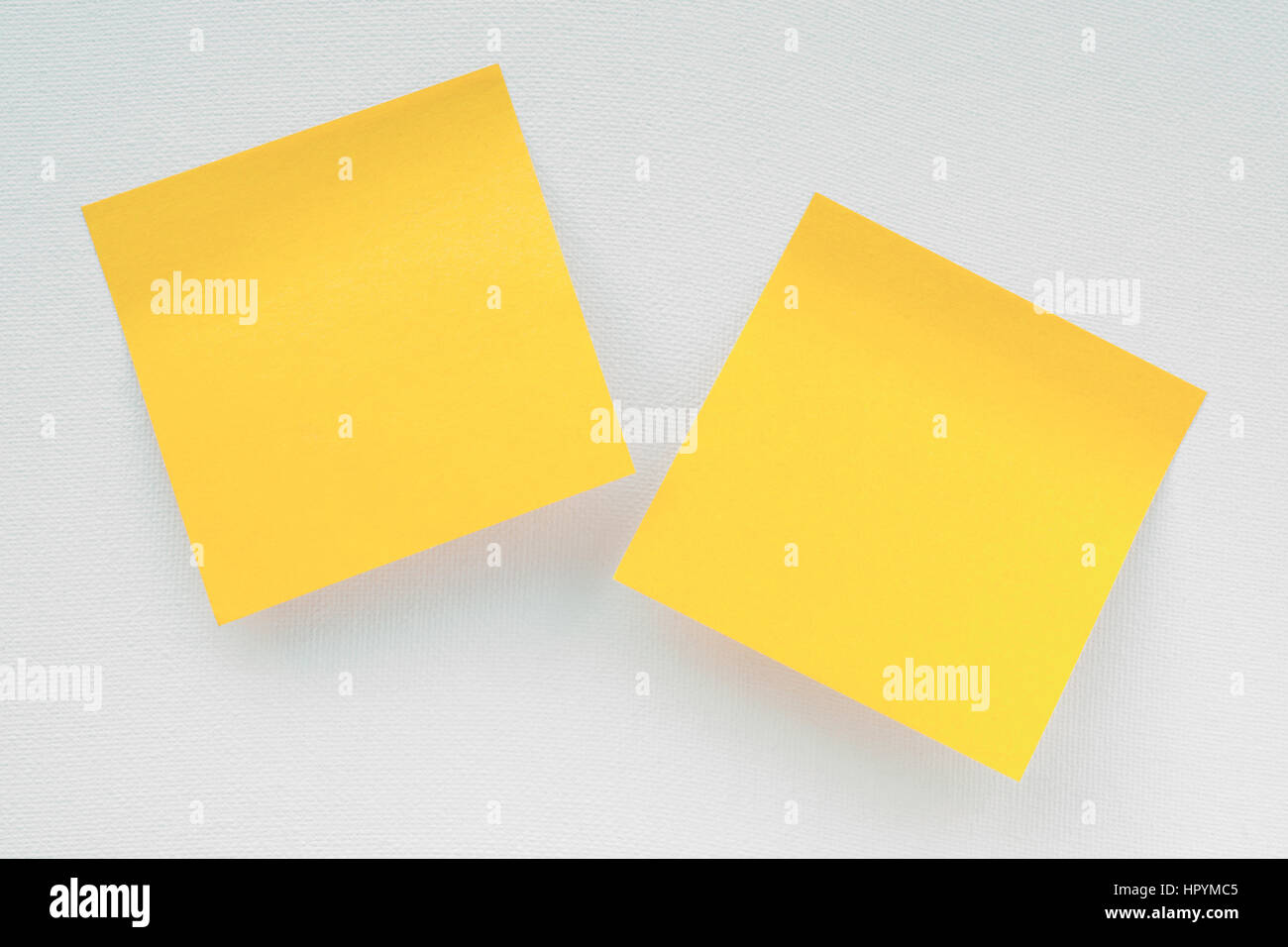 Due pezzi di colore giallo di notepaper sulla tela bianca. Modello e lo sfondo Foto Stock