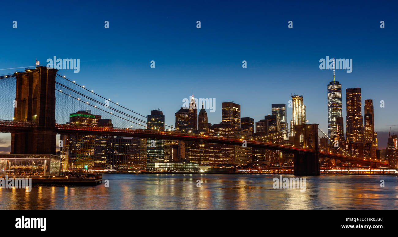 Un night shot di una illuminazione Ponte di Brooklyn con una skyline di Manhattan Foto Stock
