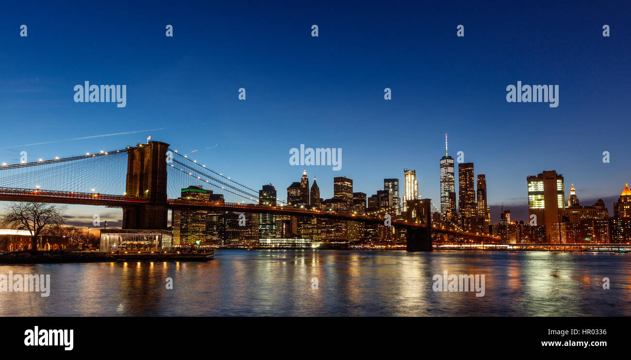Un night shot di una illuminazione Ponte di Brooklyn con una skyline di Manhattan Foto Stock