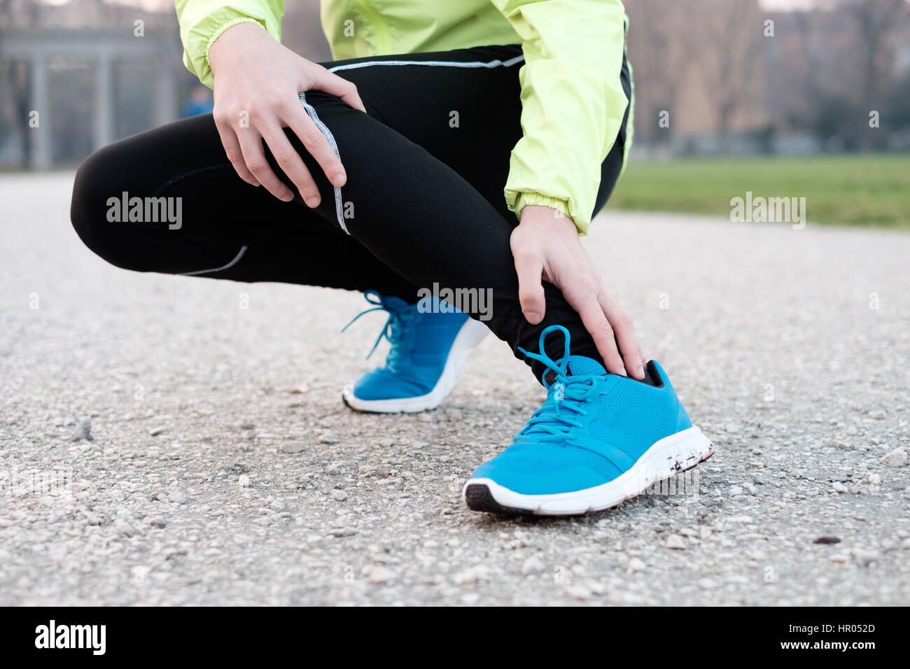 Runner con caviglia infortunata mentre la formazione nel parco della città in condizioni di clima freddo Foto Stock
