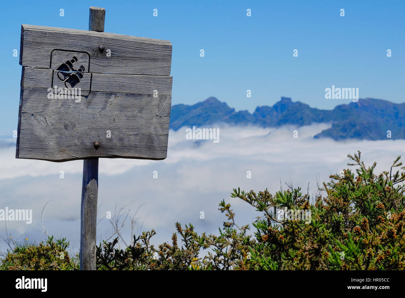 Vecchio cartello in legno con illustrato un paio di binocoli su un punto di vista al di sopra delle montagne Foto Stock