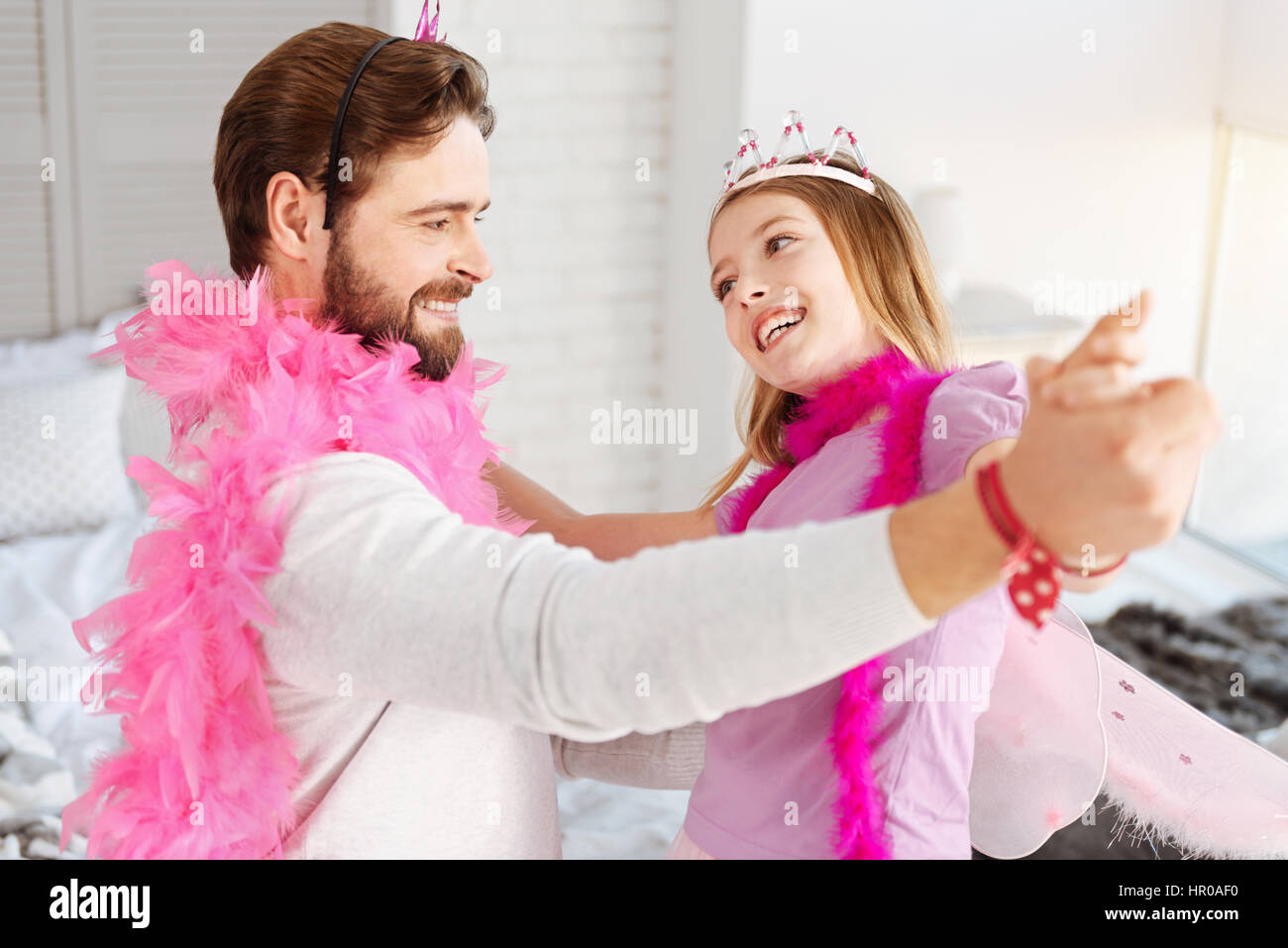 Credere a me. Giovane uomo barbuto che indossa il ponticello bianco e rosa giù per mano di sua figlia mentre guardando il suo Foto Stock