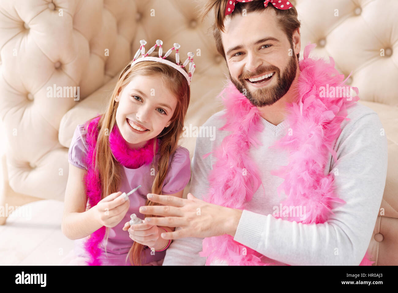 Essere di buon umore. Sorridente ragazza di colore rosa che indossa la corona sul suo capo azienda Spazzola per unghie nella mano destra mentre si posa su telecamera Foto Stock