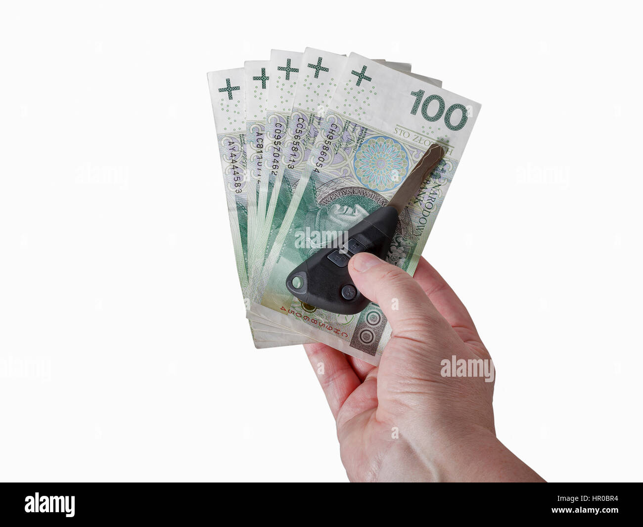 Man mano che tiene lo zloty polacco cento banconote e le chiavi dell'auto isolati su sfondo bianco closeup con spazio di copia Foto Stock