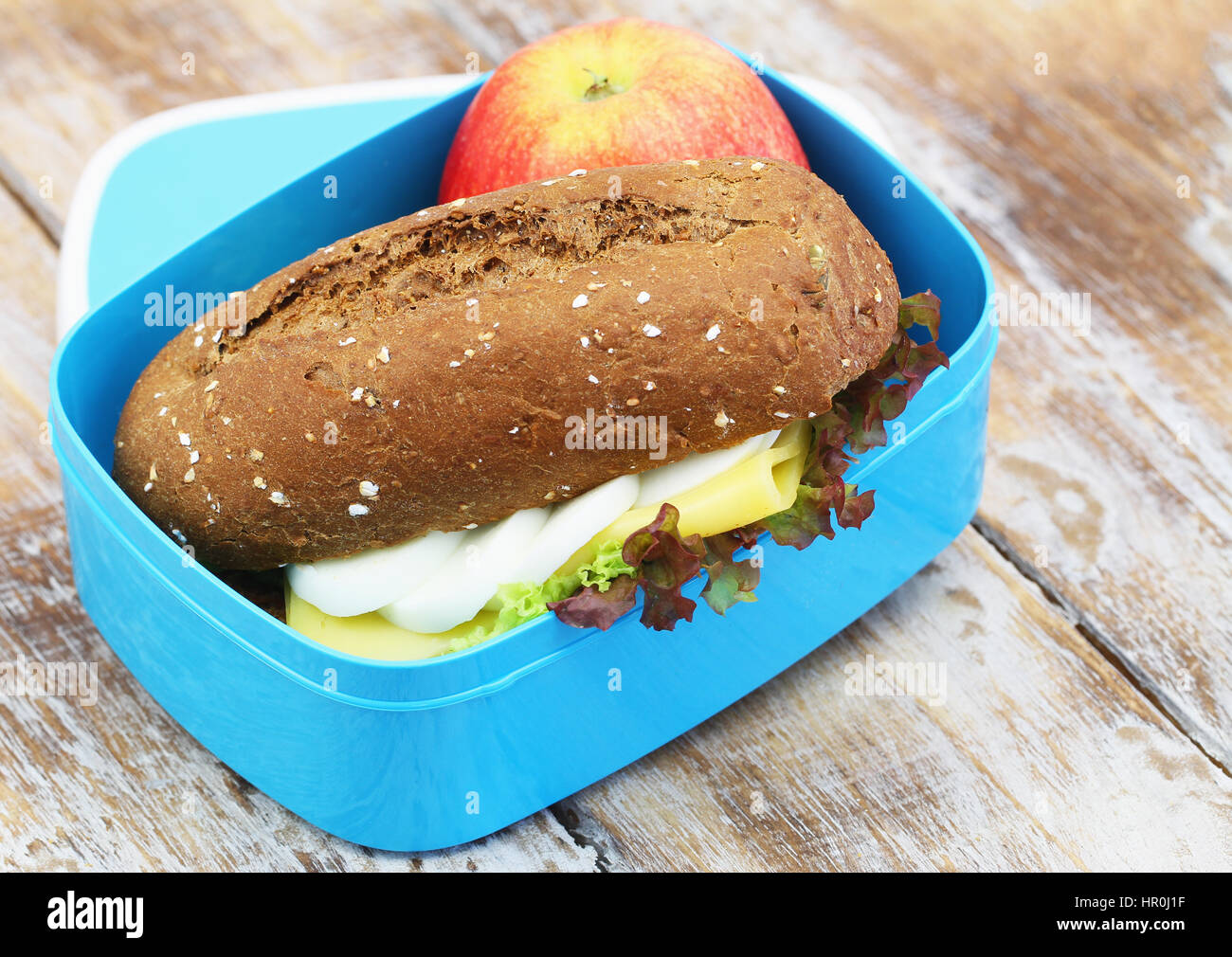 Un sano pranzo al sacco contenente il rullo di marrone con formaggio e uova e mela rossa Foto Stock