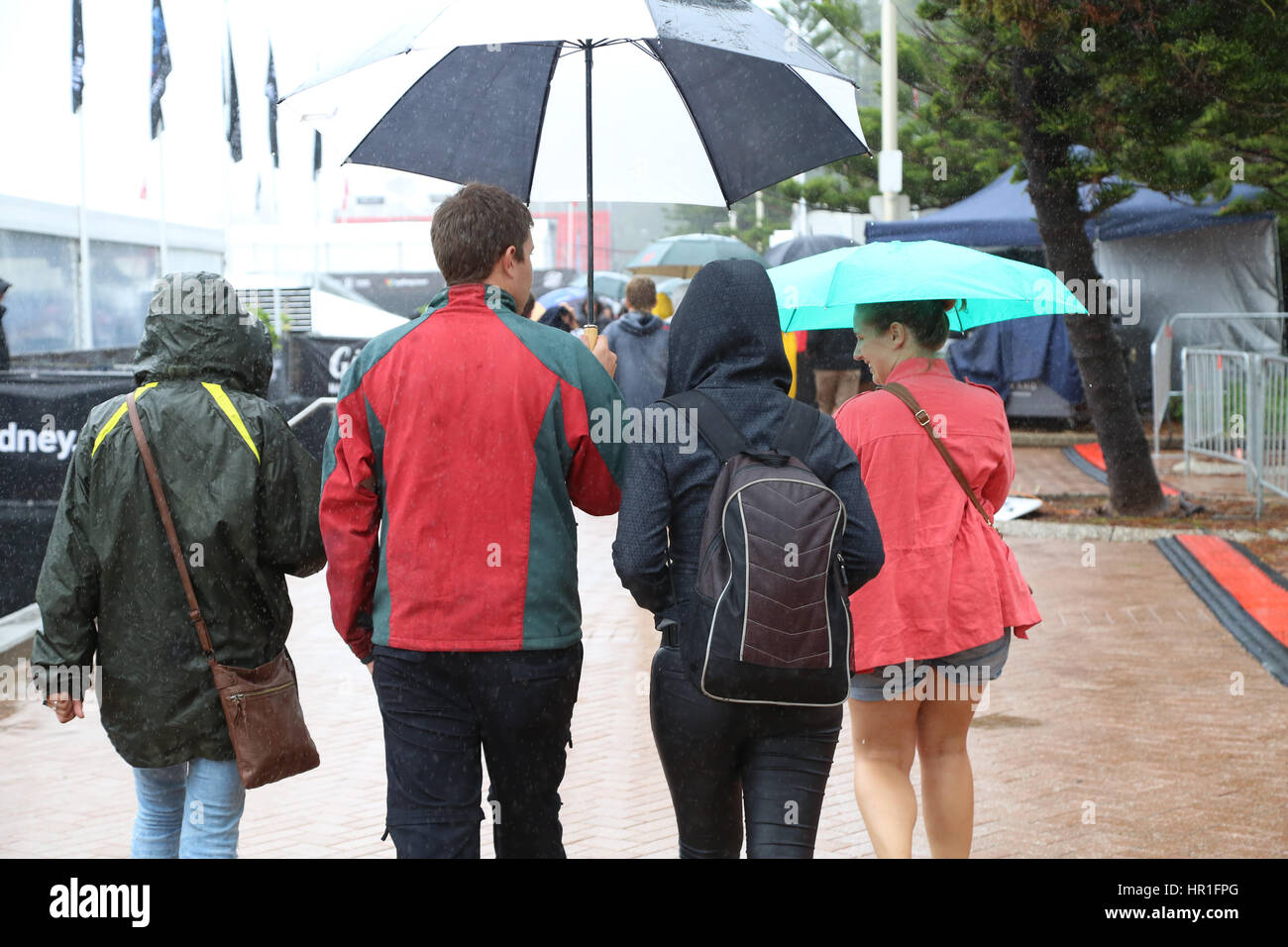 La gente cammina accanto a Manly Beach sotto la pioggia nel primo giorno della Australian Open di surf. Foto Stock