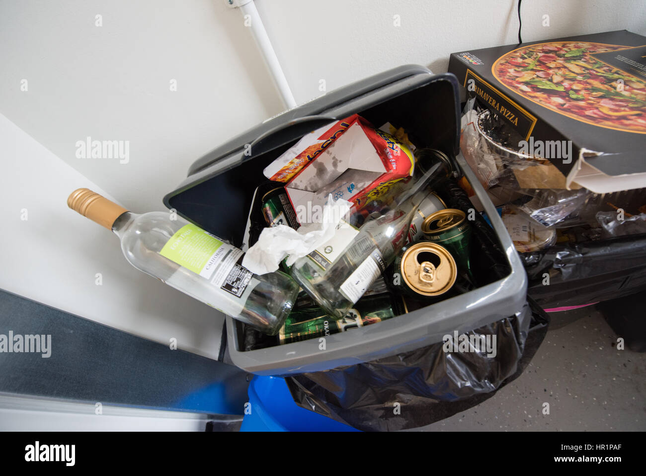 Traboccante di sporco in plastica da cucina swing scomparti pieno di spazzatura, scatole per pizza, bottiglie di vino e lattine di birra in una sala studenti del residence cucina comune Foto Stock