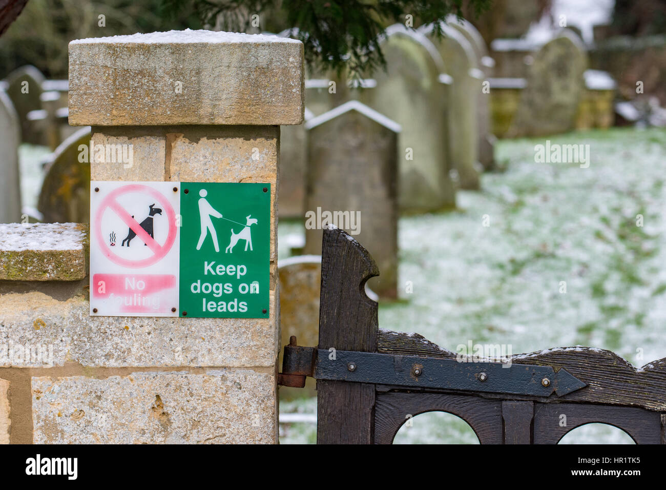 Tenere i cani in segno di piombo in corrispondenza di un ingresso alla chiesa di San Lorenzo cimitero, Mickleton, Gloucestershire Foto Stock